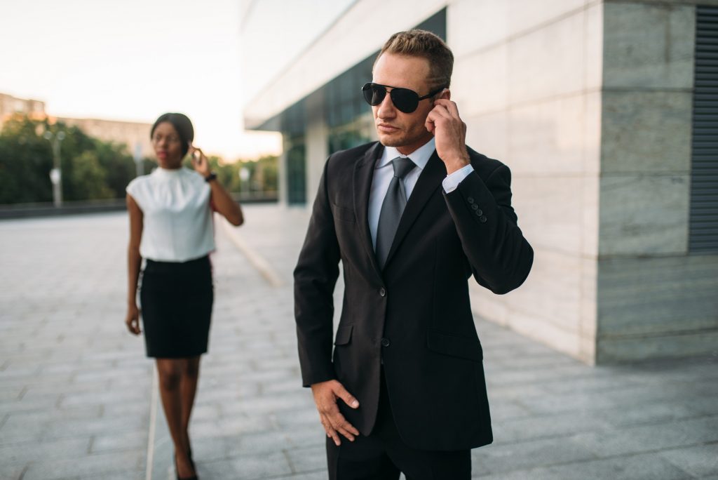 Bodyguard in sunglasses and black business woman